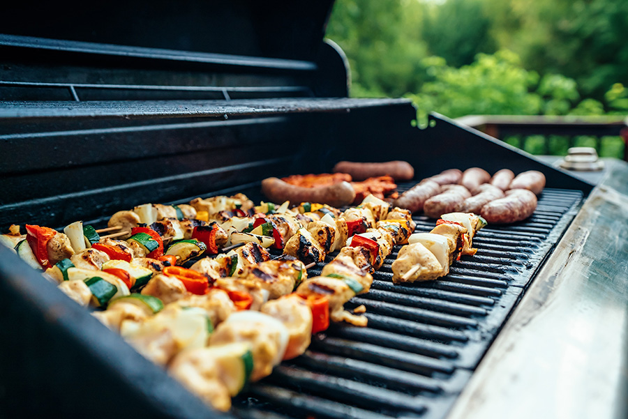 kebabs and sausages cooking on a backyard grill